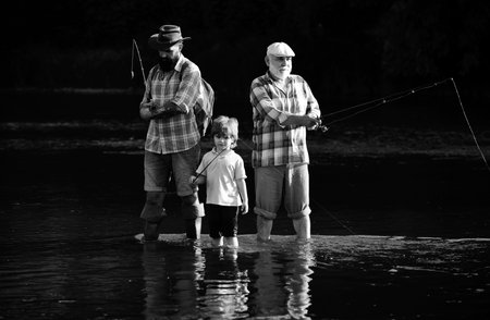 Fly fishing for trout. Senior man fishing with son and grandson. Fishing became a popular recreational activity.の写真素材