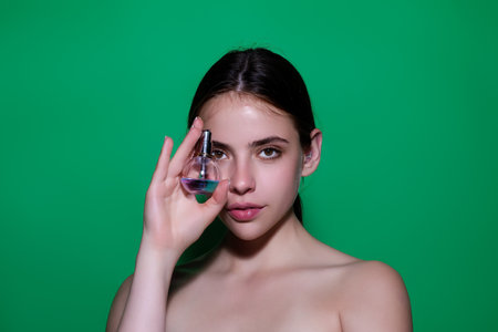 Woman with bottle of perfume smelling aroma.の写真素材