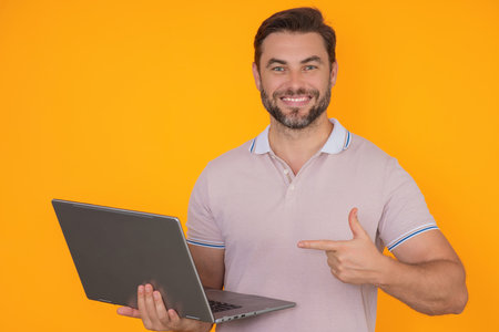 Man working on laptop in studio. Man checking email on laptop, writing message in social network, using internet, searching information on laptops. Man using laptop computer isolated in studio.の写真素材