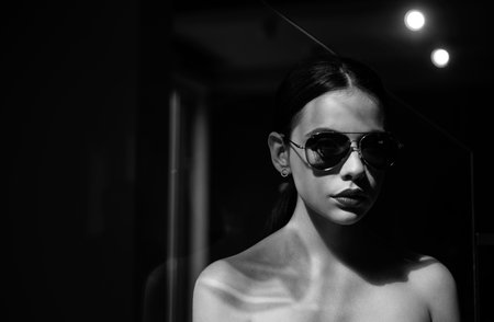 Beautiful young model with big glasses-close up. Beautiful fashion model posing with glasses. Close-up portrait of a beautiful charming young attractive lady. Fashionable youth style. Female fasion.の写真素材