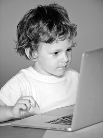 Closeup portrait of clever child boy pupil with laptop. Child from elementary school. Cheerful smiling child use laptop computer. Cheerful smiling little pupil having fun with notebook.の写真素材