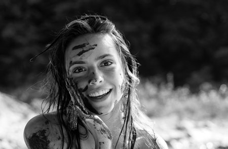 Woman with natural mud mask. Beauty treatment and skincare. Happy girl applying black dirty face mask. Mud healthy scrub.の写真素材