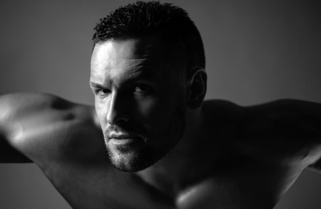 Muscular man looking at camera. Handsome muscular shirtless man. Naked shoulders.の写真素材