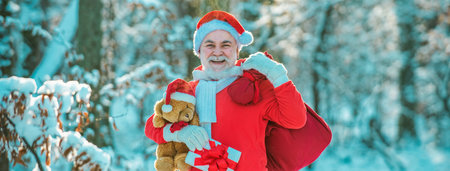 Real Santa Claus in red cap pulling large red gift sack. Santa with a huge bag.の写真素材