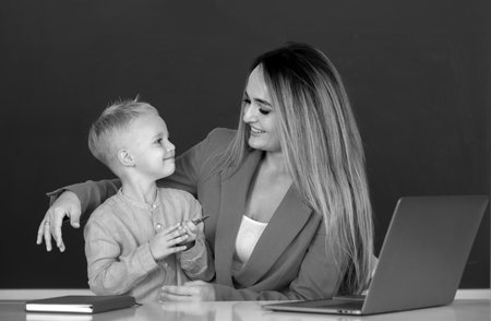 Mother and son together using computer laptop. School child learning education online lesson. Teacher helps school kids to learn lesson.の写真素材