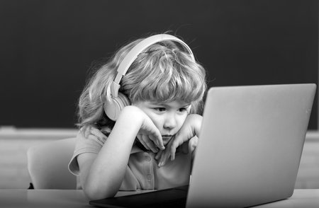 Serious child boy in headphones study online, child in earphones take Internet web lesson.