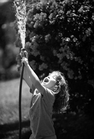 Adorable little boy is watering the plant outside the house, concept of plant growing learning activity for kid and child education for the tree in nature.の写真素材