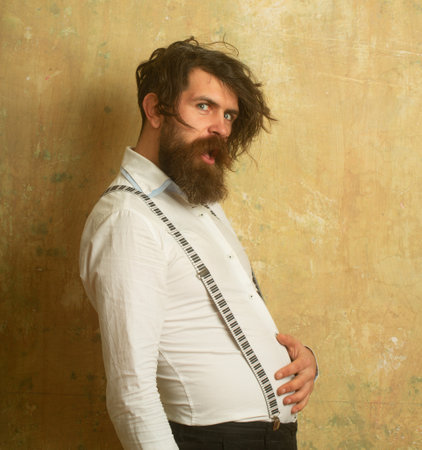 Funny bearded man with uncombed disheveled hair holding her stomach belly.の写真素材