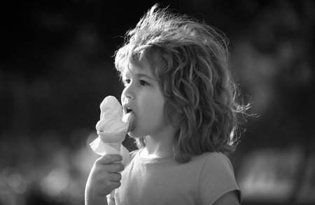 Close up head shot of child eating ice cream. Kids face, little boy portrait.の写真素材