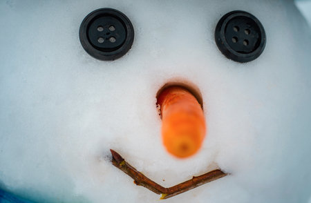 Happy funny snowman in the snow. New year Christmas concept. Snowman with red nose and black eyes button.の写真素材