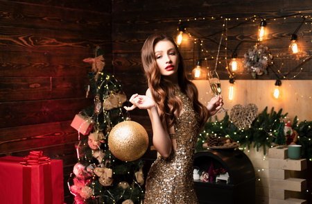 Portrait of woman holding big golden christmas bauble. Young woman with Christmas decoration. Santa girl celebrate winter holidays hold christmas balls.の写真素材