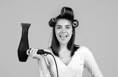 Woman with hair dryer. Funny girl with straight hair drying hair with professional hairdryer.の写真素材