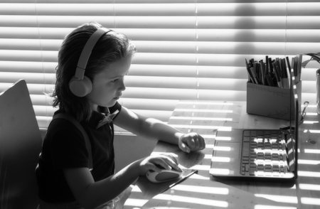 Homeschool little student learning virtual internet online class from school teacher by remote meeting. Teaching math or english by using headphone.の写真素材