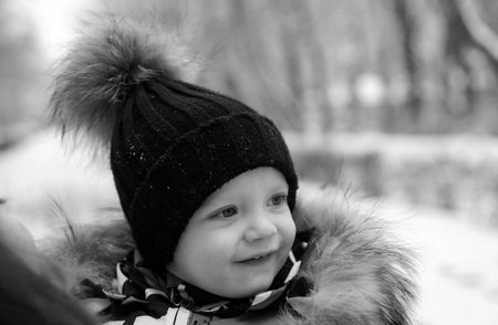 Funny laughing baby in winter outside. Cute toddler kid in a warm snowsuit and hat discovered winter...