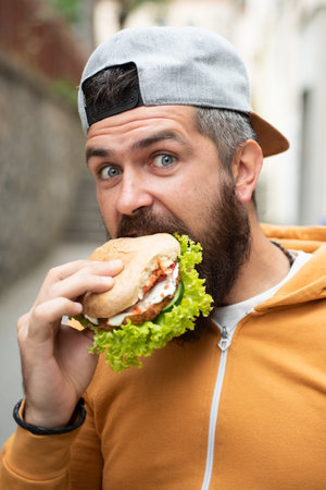 Bearded guy eats fast food. Burger is not helpful food. Very hungry guy. Hunger Man eat Hamburger...