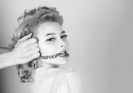 Redhead woman close up portrait with golden chain in mouth.