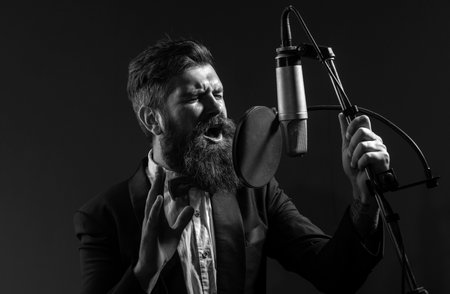 Singing man in a recording studio. Music festival. Expressive bearded man with microphone. Karaoke signer, musical vocalist.の写真素材