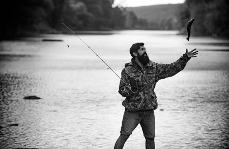 Young bearded man fishing at a lake or river. Flyfishing.の写真素材