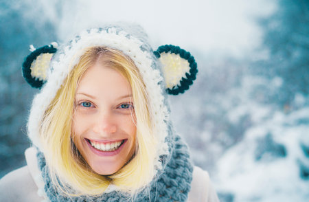 Beautiful winter portrait of young woman in the winter snowy scenery. Winter woman portrait outdoor. Model wearing stylish knitted winter hat and gloves.の写真素材
