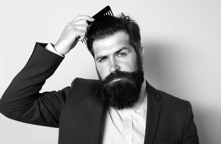Man hairstyle, modern haircut. Man styling his hair with a comb. Bearded man with beard, bearded gay. Barbershop concept. Mustache men.の写真素材