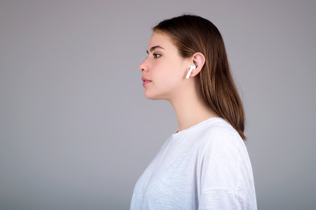 Woman listening to music with earphones. Girl with headphones, wireless earphones. Listening music in earphone, studio. Earphones in ear. Woman using headphones. Ear buds, wireless earbud earphone.の写真素材