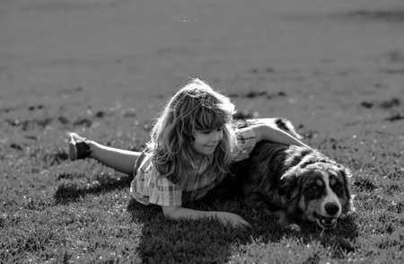 Child hugging a dog in outdoor. Kid boy lovingly embraces his pet dog. Cute child with a puppy dog, outdoor summer.の写真素材