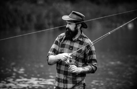 Young bearded man fishing at a lake or river. Flyfishing.の写真素材