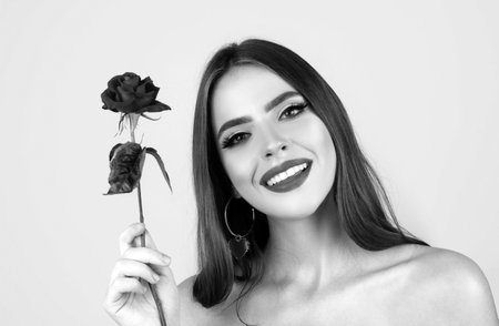 Beauty woman with red rose. Fashion girl face with rose in hand. Red lips. Vogue spring summer style. Birthday day.の写真素材