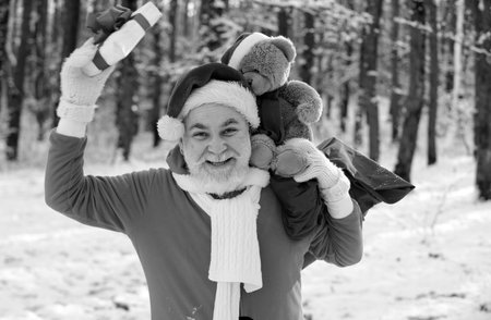 Funny Santa with Gift and teddy bear on Christmas Eve outside.の写真素材