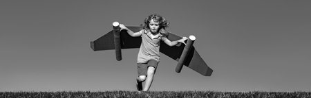 Banner with spring kids portrait. Happy child running with toy wings against summer sky background. Kids success, leader and winner concept.の写真素材