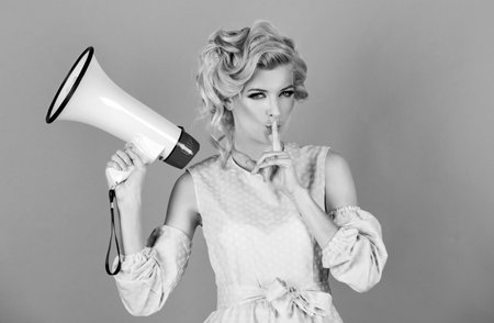 Beauty woman with megaphone isolated on pink. Young beautiful woman screaming in megaphone, isolated on background studio portrait.の写真素材