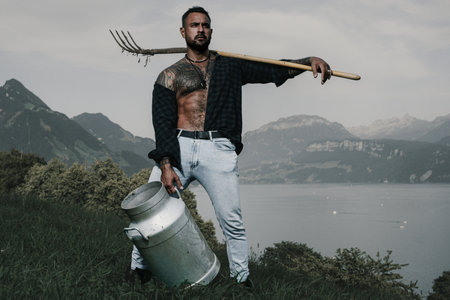 Farmer work with pitchfork, hayfork. Farmers day. Farmer working on farm. Strong farmer work in field. Farmers natural green environment. Mountain farmer in Switzerland Alps on milk farm.の写真素材