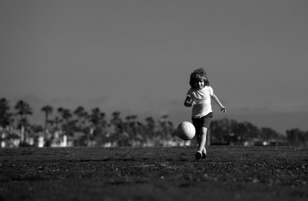 Boy child playing football on football field. Kid playing soccer. Kids training soccer.