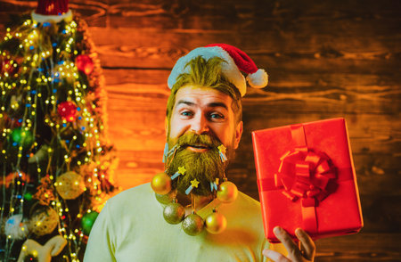 Delivery gifts. New Year, Christmas card. Hipster modern Santa Claus wishes Merry Christmas. Styling Santa Claus with a long beard posing on the wooden background.の写真素材
