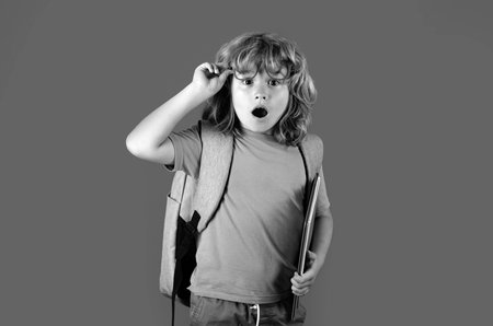 Back to school. School child with book on isolated background. Surprised amazed emotions of school boy.の写真素材