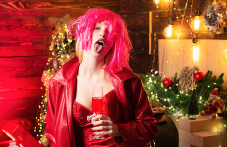 Crazy sexy drunk girl in a New Years dress and pink wig showing her tongue at camera. Christmas...
