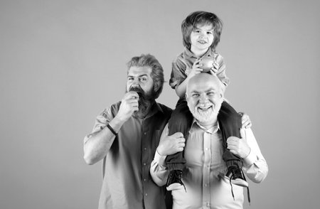 Grandfather father and grandson hugging and eating apple. Men in different ages.の写真素材