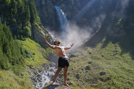 Man in Alps waterfall. Sexy man. Man freedom lifestyle. Meditating in nature. Hispanic man practicing yoga. Lifestyle relaxation concept, summer meditation on nature. Calmness and relax in nature.の写真素材