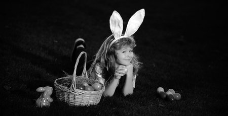 Easter egg hunt in garden. Child boy playing in field, hunting easter eggs. Bunny kids with rabbit...