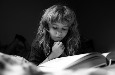 Child boy reading book. Kids reading story. Kids face with night light. Concept of education and reading. Kids development of the imagination.の写真素材