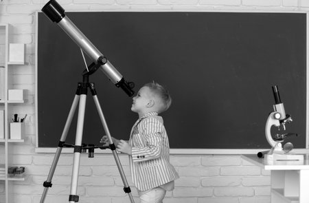 School boy with telescope learning astronomy lesson at school.