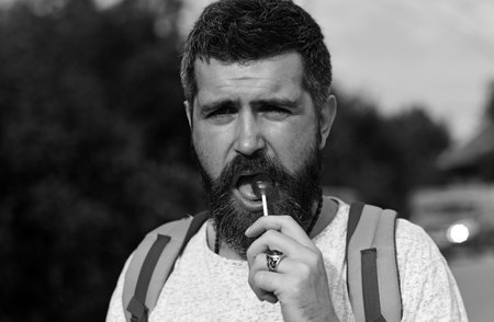 Hiker man with backpack hiking in beautiful forest. Gay lick lollipop.の写真素材