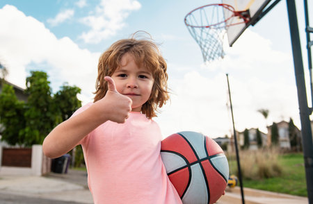 Little child boy playing basketball with basket ball, , thumbs up.. Active kids lifestyle.の写真素材