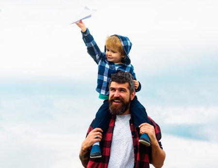 Portrait of happy father giving son piggyback ride on his shoulders. Child play with toy plane. Family travel vacation, fathers day.の写真素材