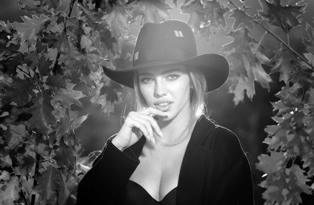 Closeup portrait of a sensual girl in hat with autumn leaves. Romantic sexy autumn female model.の写真素材