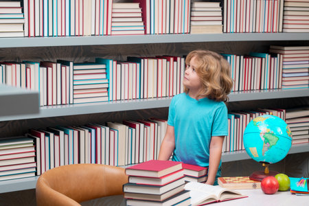 School boy with stack of books in library. Kid boy from elementary school with book. Little student, smart nerd pupil ready to study. Concept of education and learning.の写真素材
