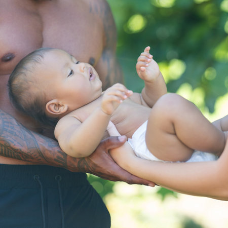 Happy baby. Close up of Biracial baby lying on parents hands. Father and Mother hug Biracial baby child. Multiracial Fathers and mothers hand for baby. Child in tender caring hands. Babies love.の写真素材