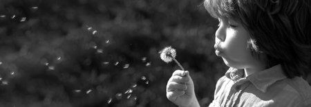 Banner with spring kids portrait. Spring or summer kid blow dandelions flower on walk and grass background. Soul harmony concept.の写真素材