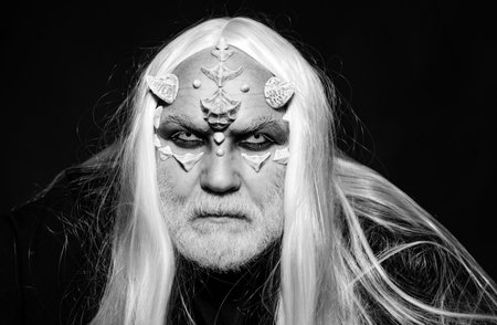 Horned Devil in his home - Ancient style. Vampire man with white eyes. Man evil with horns. Horror and fantasy concept. Mysterious warrior enchanted to have thorns on his face.の写真素材