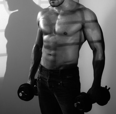 Shirtless bodybuilder is doing exercise with dumbbell.の写真素材
